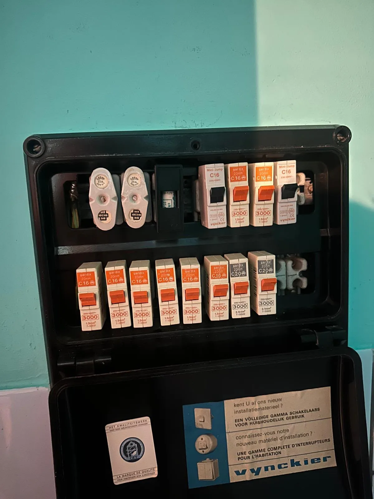 Oud zwart verdeelkastje met smeltzekeringen en verouderde automaten